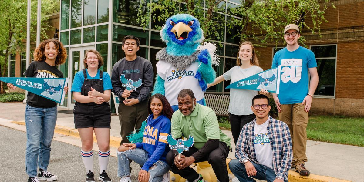 Group of AACC students wearing AACC gear and posing with Swoop.